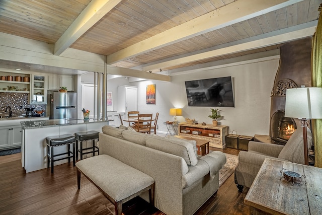 living room featuring beam ceiling, wooden ceiling, dark wood-type flooring, and sink