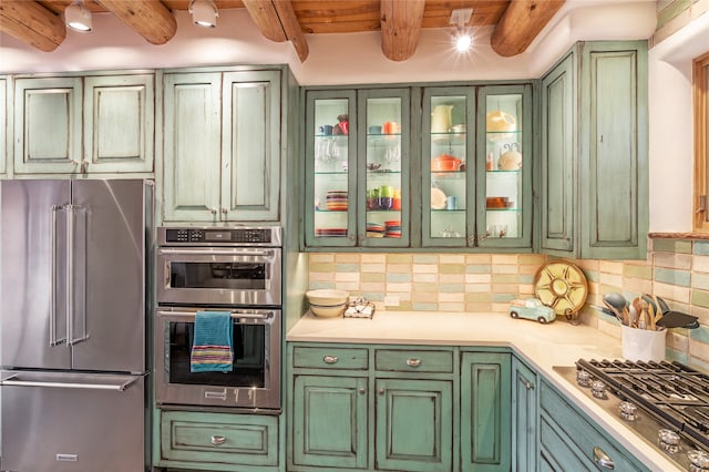 kitchen featuring ceiling fan, stainless steel appliances, tasteful backsplash, beamed ceiling, and green cabinetry