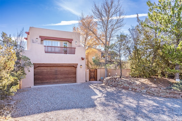 pueblo revival-style home with a balcony and a garage