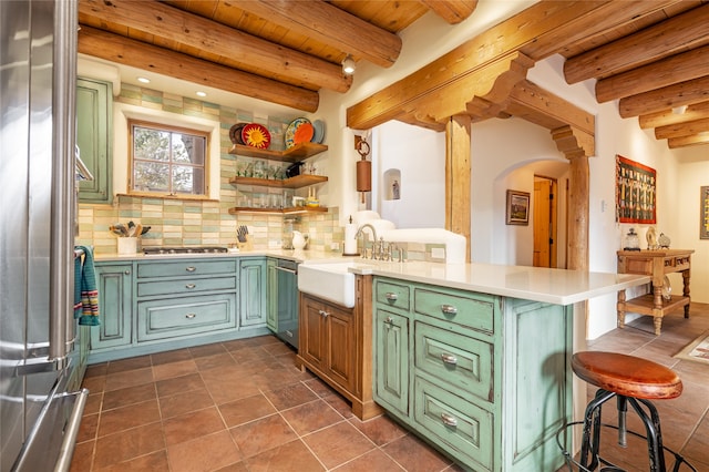 kitchen with beamed ceiling, kitchen peninsula, sink, and tasteful backsplash