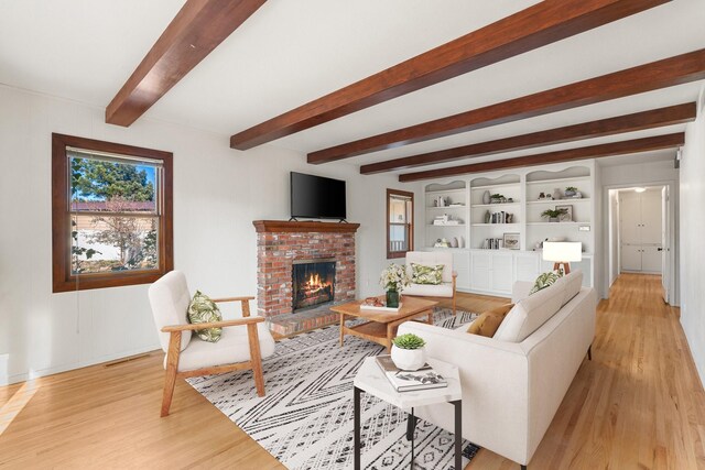 living room featuring hardwood / wood-style floors, a fireplace, beamed ceiling, and a chandelier