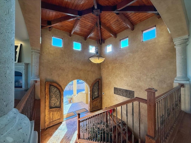 interior space with beamed ceiling, a high ceiling, ornate columns, and wood ceiling