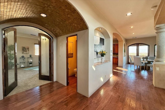 hallway featuring lofted ceiling, wood-type flooring, crown molding, and french doors