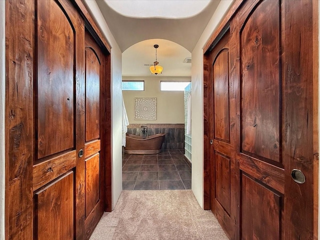 hall with dark colored carpet and lofted ceiling