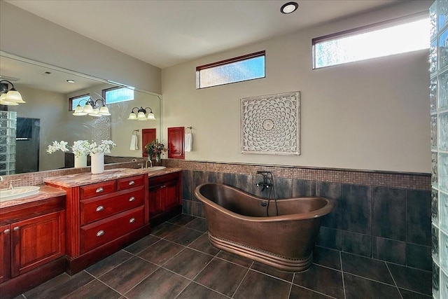 bathroom featuring tile patterned flooring, vanity, a tub to relax in, and tile walls