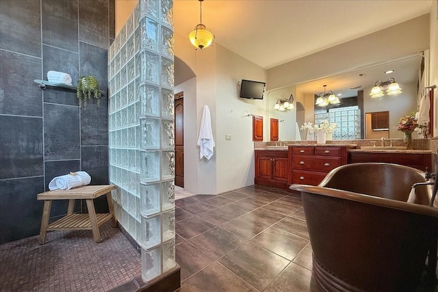 bathroom featuring vanity, a bathtub, an inviting chandelier, tile patterned floors, and tile walls