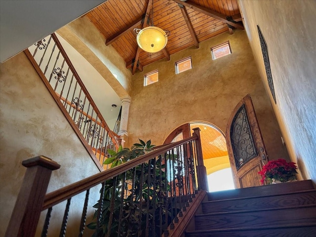 staircase with beam ceiling, high vaulted ceiling, and wooden ceiling