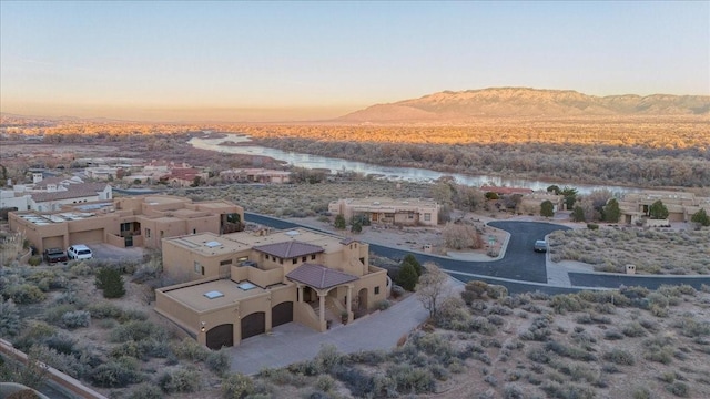 aerial view at dusk featuring a water and mountain view