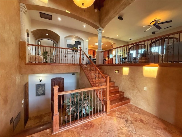 stairs featuring ornate columns and ceiling fan