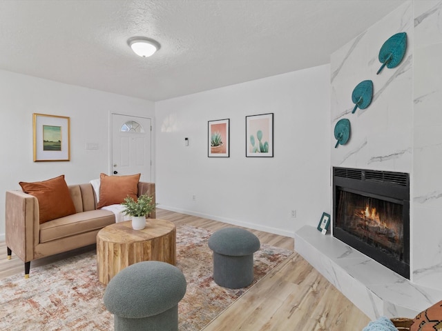 living room featuring a high end fireplace, light hardwood / wood-style floors, and a textured ceiling