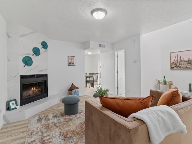 living room with a fireplace, light hardwood / wood-style flooring, and a textured ceiling