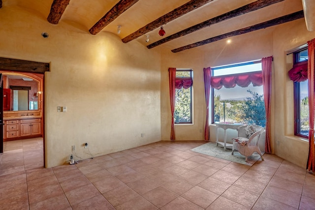 tiled empty room featuring beam ceiling and a healthy amount of sunlight