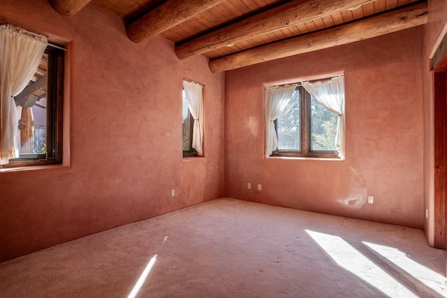 spare room featuring beamed ceiling, carpet floors, and wood ceiling