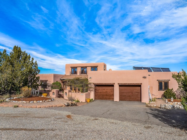 pueblo revival-style home with solar panels and a garage