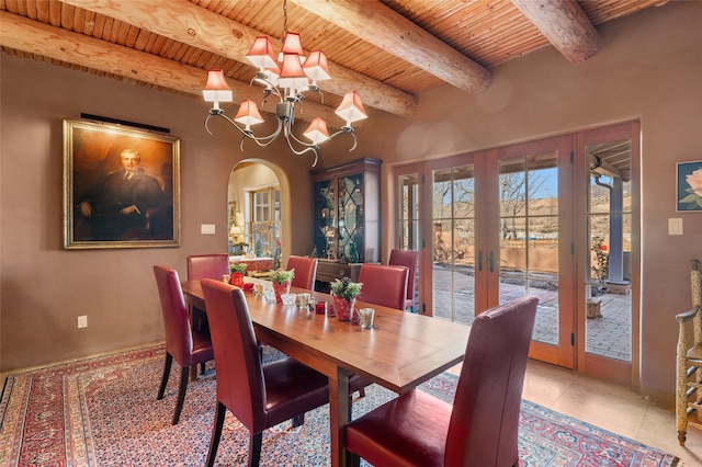 dining area with light tile patterned floors, a notable chandelier, beamed ceiling, french doors, and wood ceiling