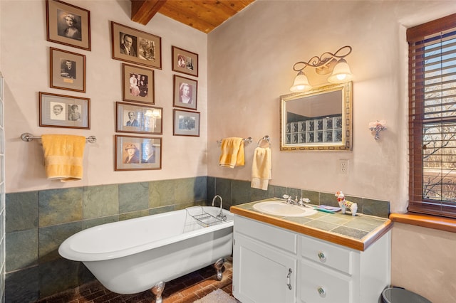 bathroom featuring tile walls, vanity, a tub to relax in, wooden ceiling, and beam ceiling