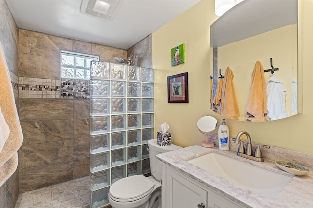 bathroom with vanity, a tile shower, and toilet