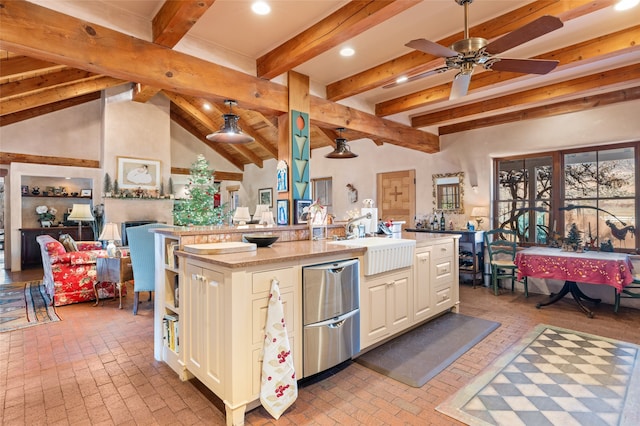 kitchen featuring a center island with sink, sink, ceiling fan, light stone counters, and beamed ceiling