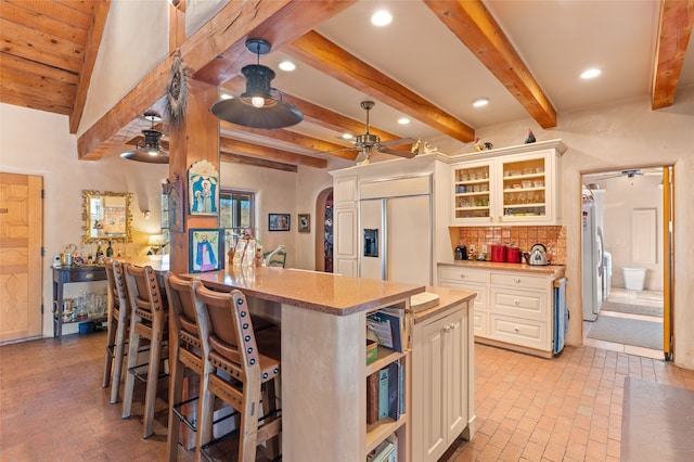 kitchen featuring a center island with sink, ceiling fan, paneled built in refrigerator, and backsplash