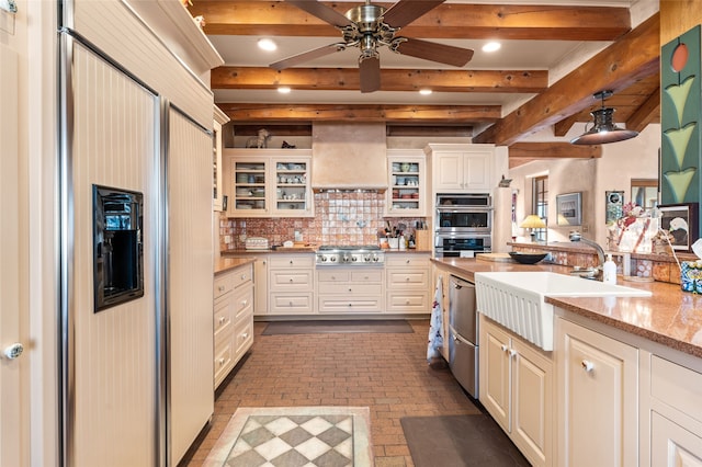 kitchen featuring appliances with stainless steel finishes, sink, backsplash, light stone counters, and premium range hood