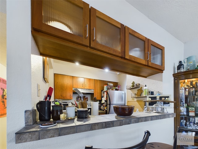 kitchen with stainless steel fridge and tile countertops