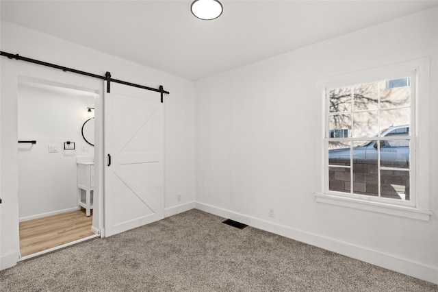 carpeted spare room featuring a barn door