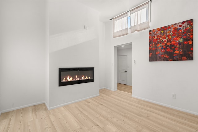 unfurnished living room with a high ceiling and light hardwood / wood-style flooring