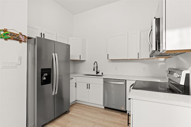 kitchen with light wood-type flooring, stainless steel appliances, white cabinetry, and sink