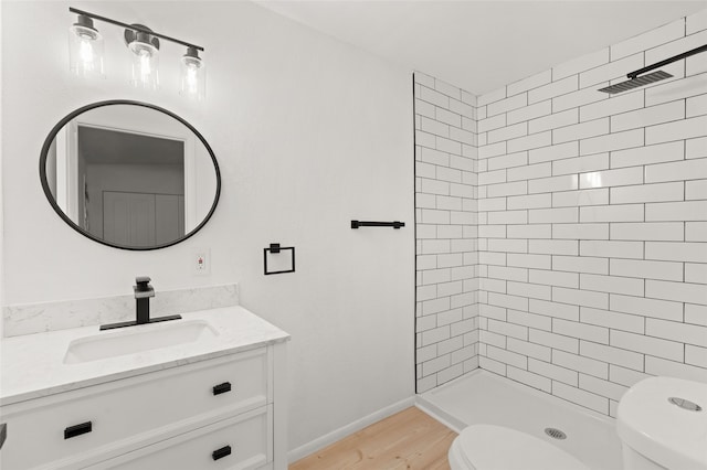 bathroom featuring vanity, toilet, wood-type flooring, and a tile shower