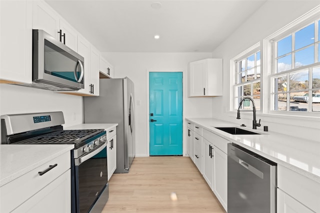 kitchen featuring light hardwood / wood-style floors, white cabinetry, sink, and appliances with stainless steel finishes