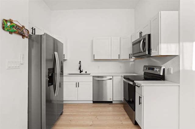 kitchen with appliances with stainless steel finishes, light wood-type flooring, white cabinetry, and sink