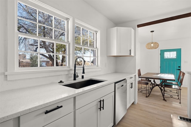 kitchen with light stone countertops, sink, decorative light fixtures, light hardwood / wood-style flooring, and dishwasher