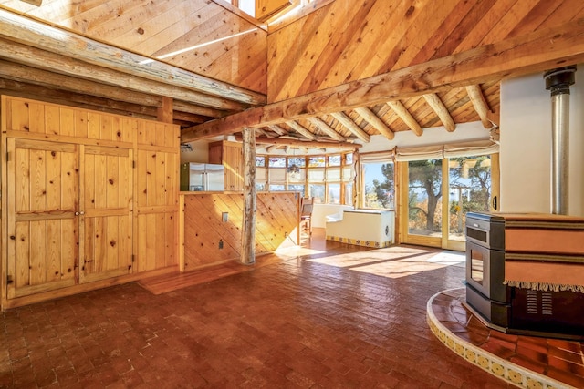 unfurnished living room with wood ceiling, vaulted ceiling with beams, a wood stove, and wooden walls