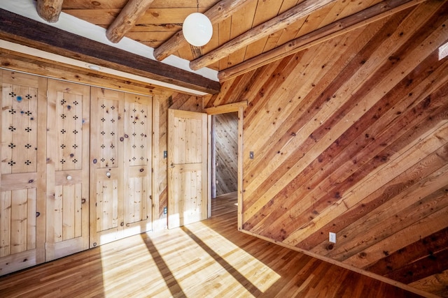 unfurnished bedroom with beamed ceiling, wooden ceiling, hardwood / wood-style floors, and wooden walls