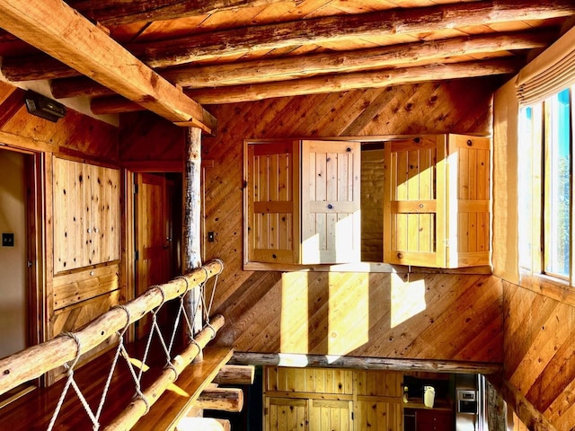 interior space featuring beamed ceiling and wood walls