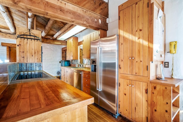 kitchen with hardwood / wood-style floors, wood counters, beamed ceiling, and appliances with stainless steel finishes