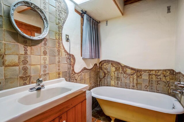 bathroom with a washtub, vanity, tile walls, and radiator heating unit