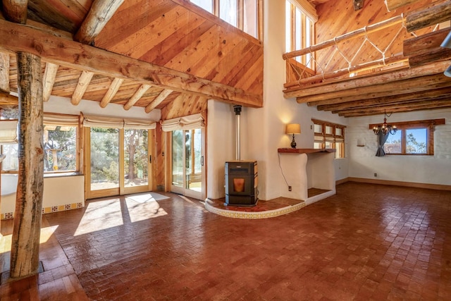 unfurnished living room with a chandelier, lofted ceiling with beams, a wood stove, and wood ceiling