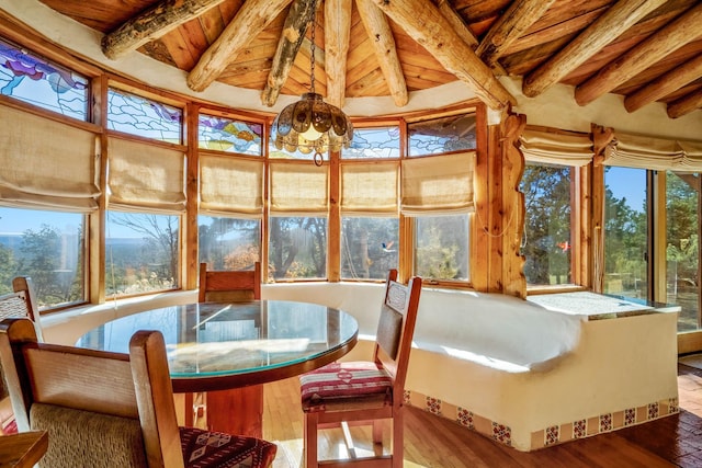 sunroom / solarium featuring a chandelier, lofted ceiling with beams, a healthy amount of sunlight, and wood ceiling