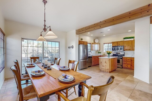 dining space with beamed ceiling, light tile patterned floors, and a healthy amount of sunlight