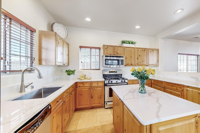 kitchen featuring sink, light stone countertops, light tile patterned floors, a kitchen island, and stainless steel appliances