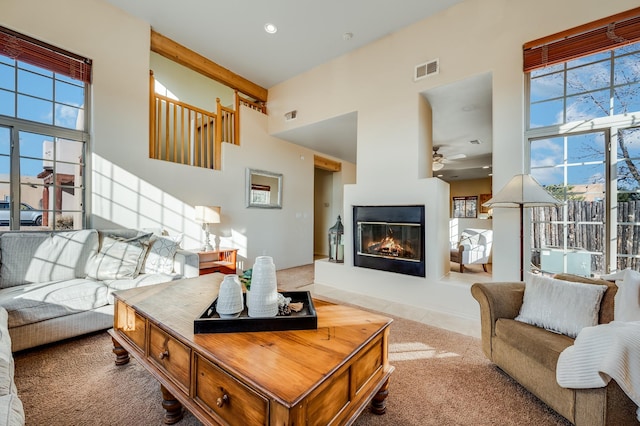 carpeted living room with a wealth of natural light, ceiling fan, and a high ceiling