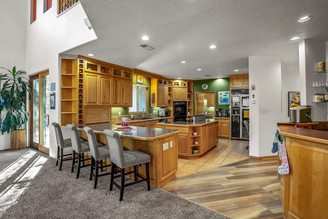 kitchen with a kitchen breakfast bar, sink, light wood-type flooring, a textured ceiling, and a kitchen island