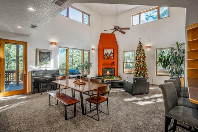 dining room featuring a towering ceiling, a textured ceiling, carpet floors, and plenty of natural light