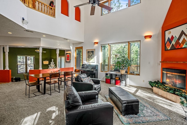 carpeted living room with a wealth of natural light, ceiling fan, and a high ceiling