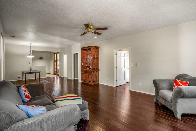 living room with dark hardwood / wood-style floors, ceiling fan, and a textured ceiling