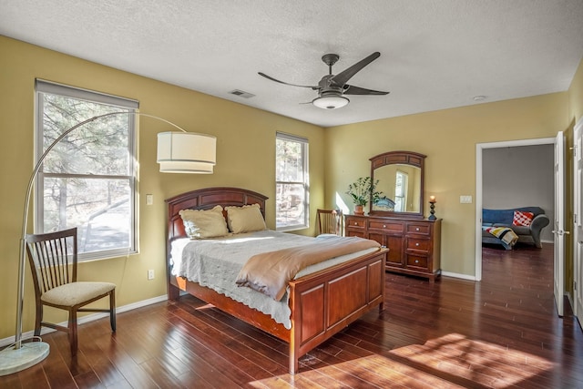 bedroom featuring a textured ceiling, ceiling fan, dark wood-type flooring, and multiple windows