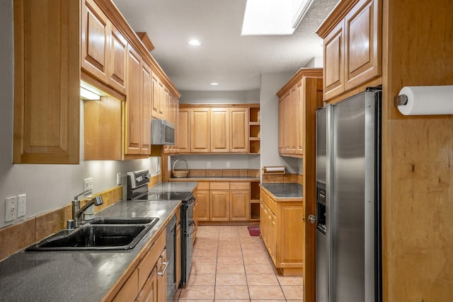 kitchen featuring appliances with stainless steel finishes, a skylight, light tile patterned floors, and sink