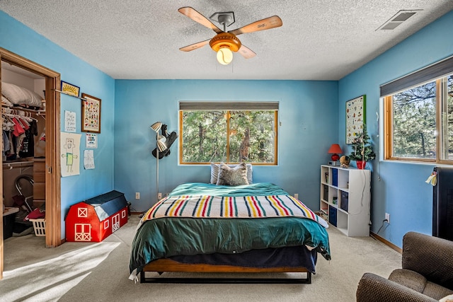 bedroom with ceiling fan, a closet, light colored carpet, and a textured ceiling