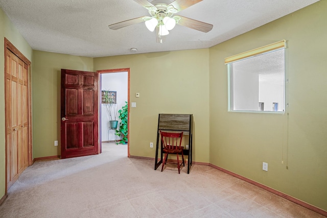 living area featuring ceiling fan, a textured ceiling, and light carpet